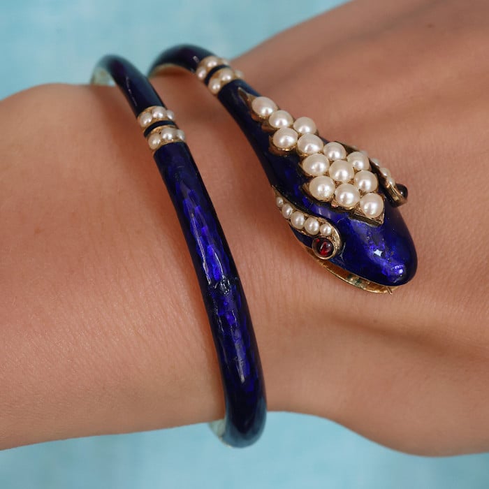 A snake bangle bracelet with pearls, ruby eyes and blue enamel, in yellow gold, modelled on a wrist