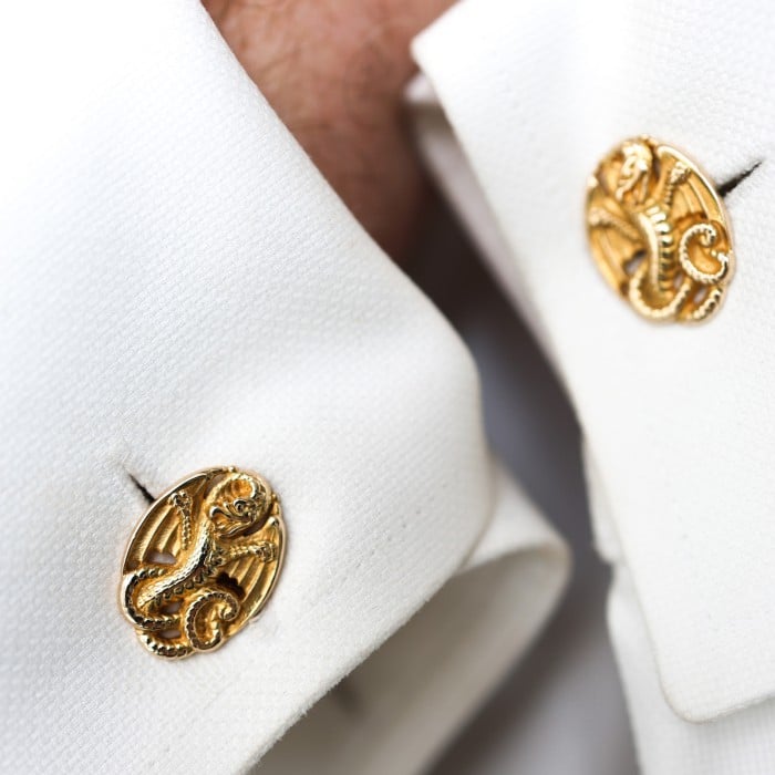 A pair of oval yellow gold cufflinks with dragon motifs, modelled in white shirt cuffs